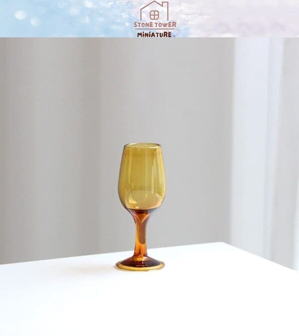 Amber-toned miniature wine glass on a white surface with soft background lighting.