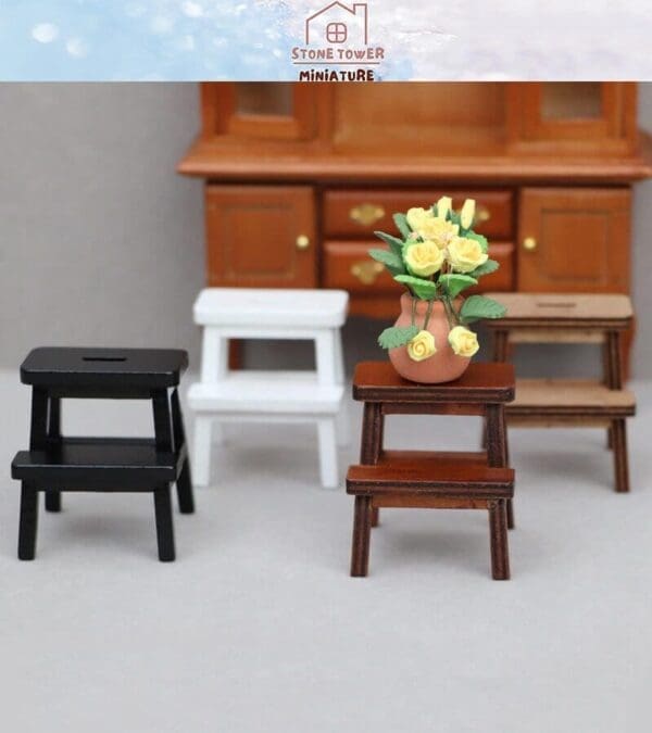 Miniature stools in black, white, and wood finish with a vase of yellow roses, set against a wooden cabinet.