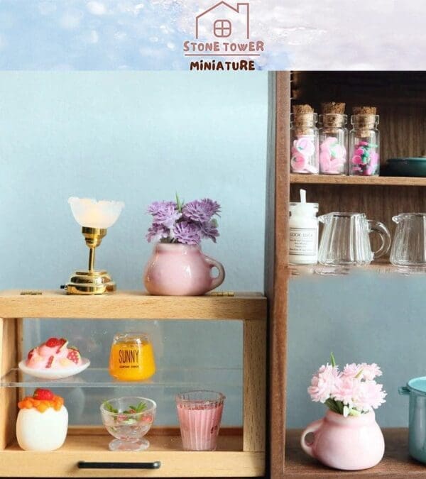 Miniature kitchen scene with pink flowers, glass containers, a small lamp, and various colorful desserts on display.