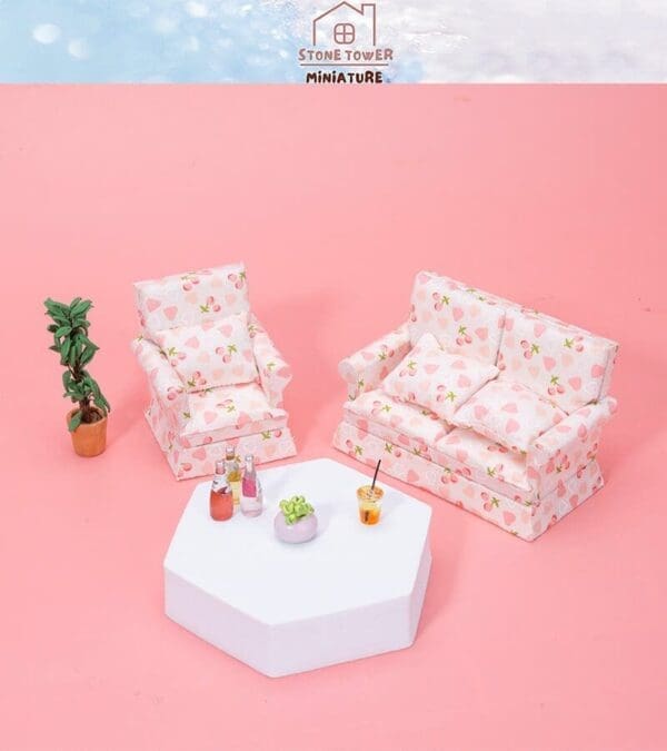 Miniature pink floral armchair, sofa, white hexagonal table with drinks, plant on a pink background.