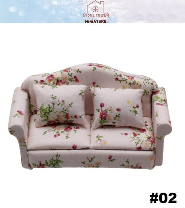 Miniature floral sofa with two matching pillows, featuring pink and green flowers on a light background.