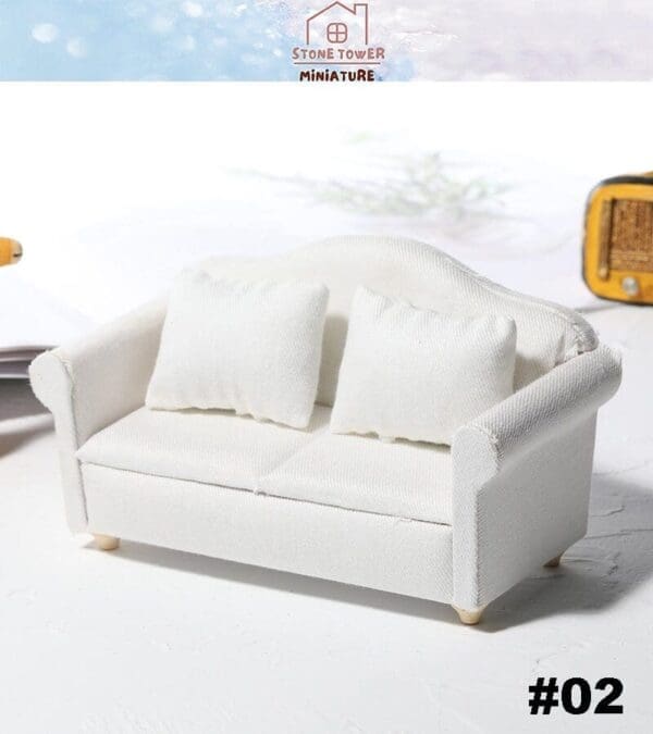 Miniature white sofa with two cushions, set against a light background, labeled "#02.