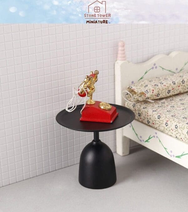 Miniature red vintage phone on black side table beside floral-patterned bed in a dollhouse room.