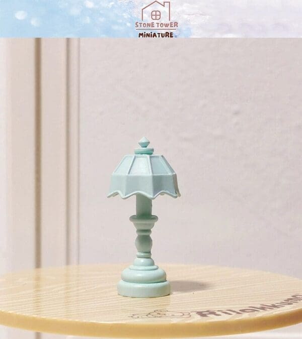 Mint green miniature table lamp on a wooden surface.