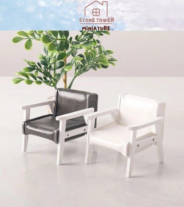 Two miniature chairs, one black and one white, with a small green plant in the background.