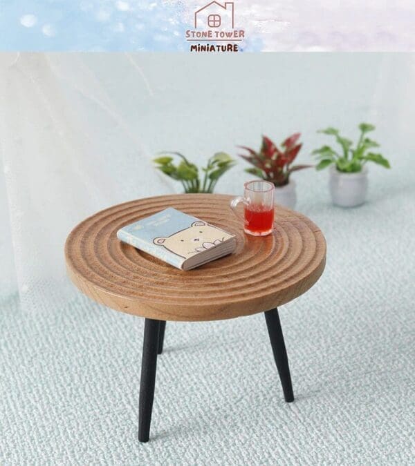 Miniature round table with bear book and red drink, surrounded by small potted plants on a textured surface.