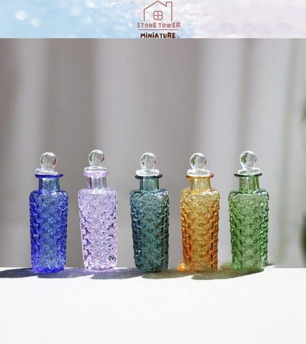 Five colorful, textured glass bottles with round stoppers arranged in a row on a light surface.