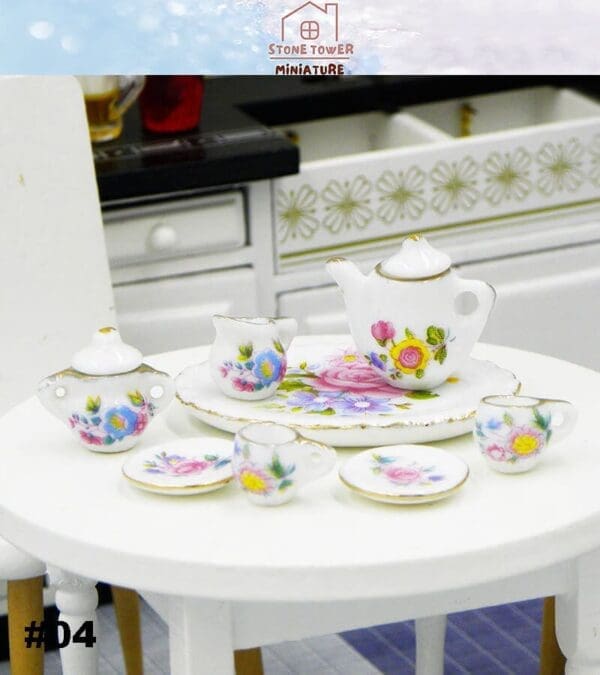 Miniature floral tea set on a round white table, with a teapot, cups, and plates, in a detailed kitchen setting.