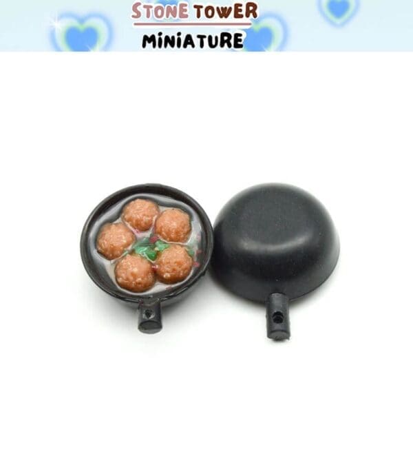 Miniature black pot with meatballs and vegetables, open to show contents, on a white background.