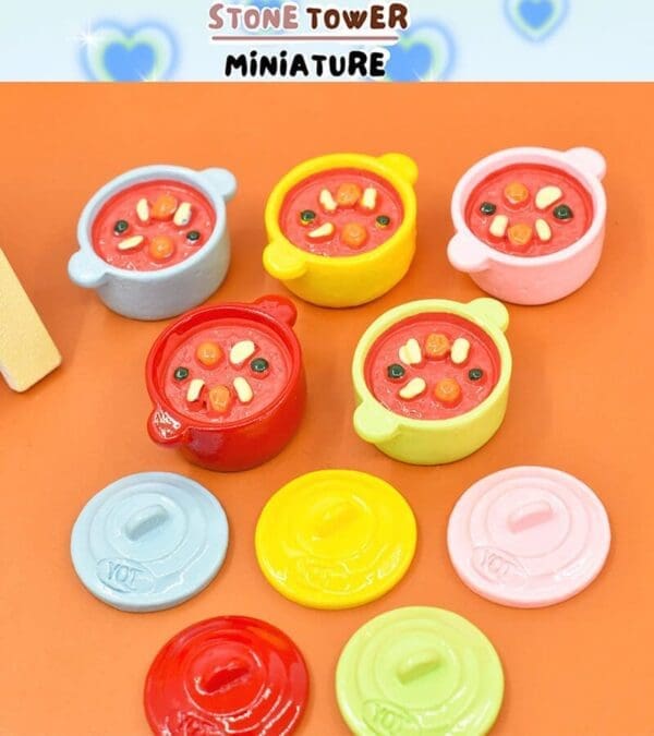 Colorful miniature pots with lids and soup, set on an orange background.