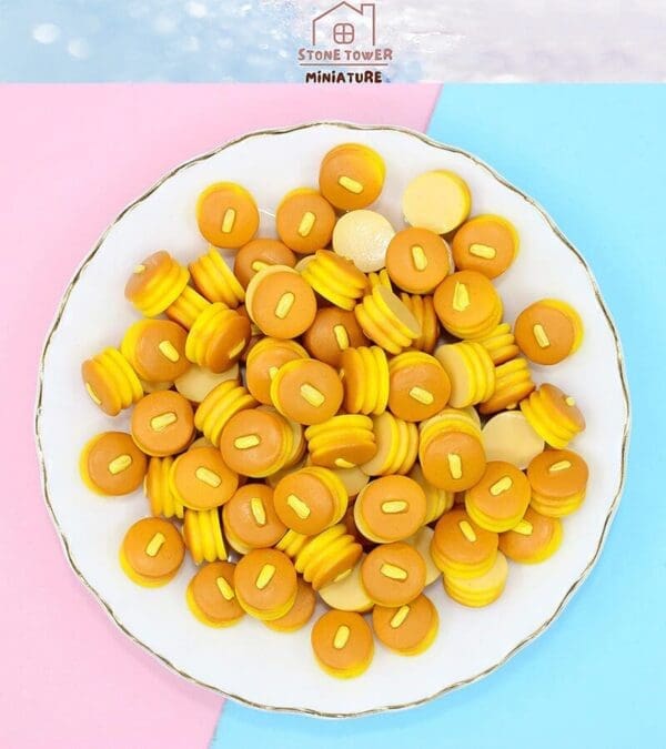 Plate of miniature pancake charms with butter slices on a pastel background.