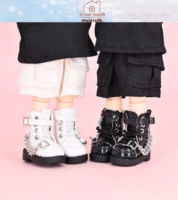 Miniature dolls in black and white boots with matching pants on a pink background.