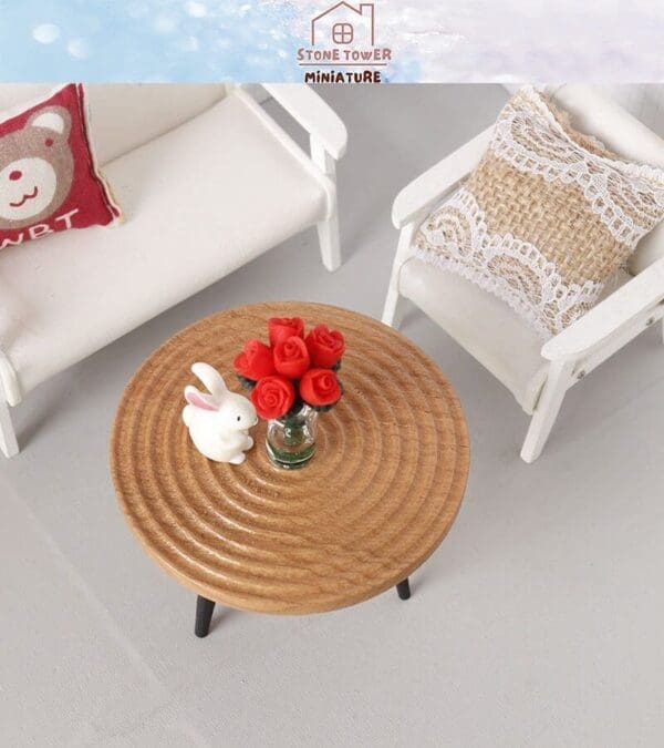 Miniature wooden table with a white rabbit figurine and red roses, flanked by white chairs with decorative pillows.