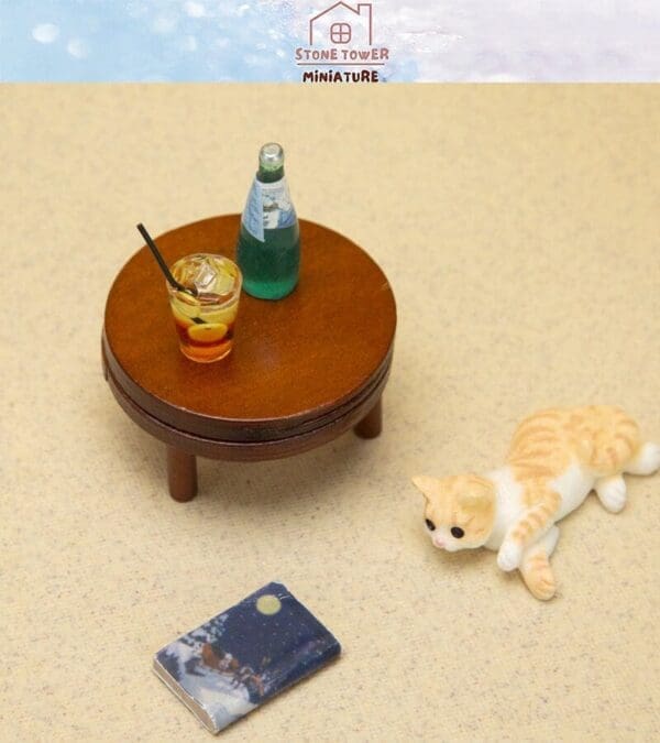 Miniature round table with drinks, a small laying cat figurine, and a book on beige carpet.