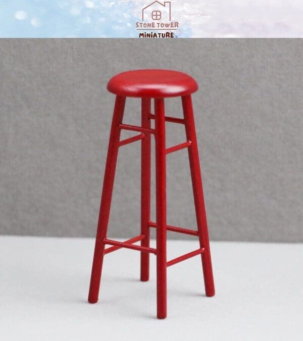 Miniature red bar stool with a round seat and four legs against a gray background.