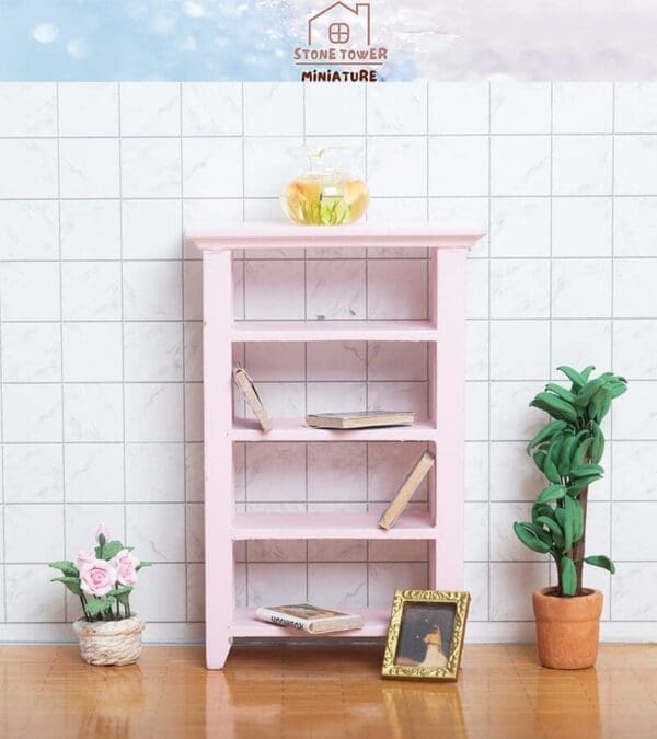 Miniature pink bookshelf with books, a framed photo, fishbowl, and plants against a tiled wall.