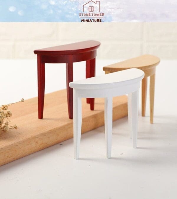 Three miniature half-moon tables in red, white, and wood finish on a wooden surface.