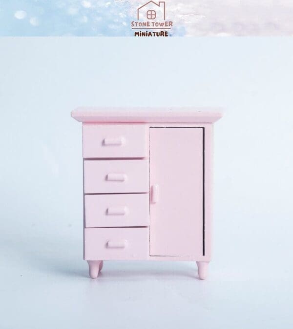 Pink miniature cabinet with three drawers and a door, set against a light blue background.