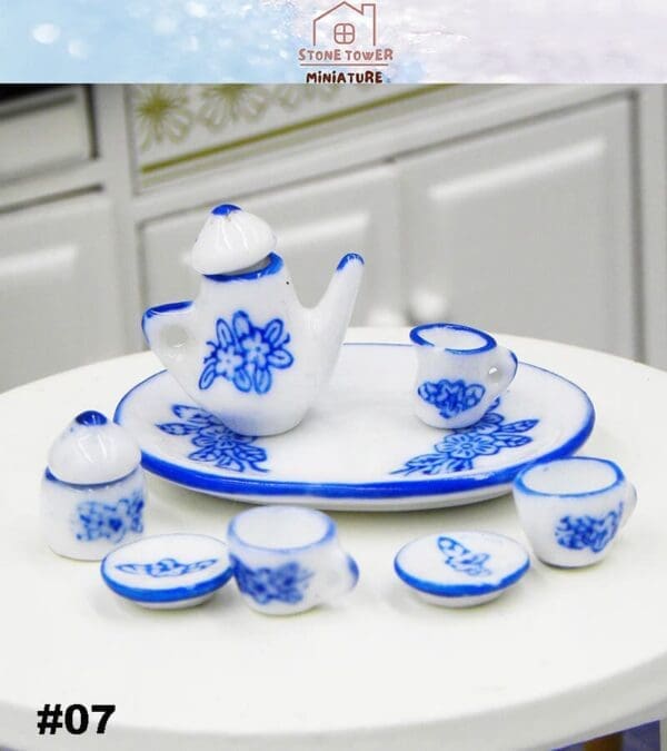 Miniature blue and white ceramic tea set with floral designs, including a teapot, cups, saucers, and a plate.