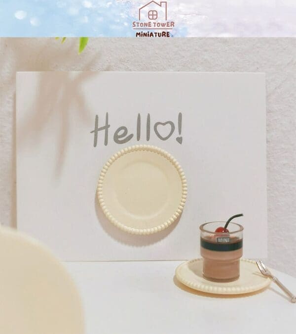 Miniature dessert and fork on a plate with "Hello!" card in the background, promoting Stone Tower Miniature.