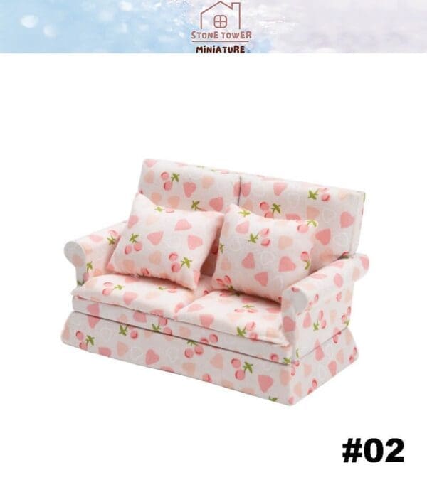 Miniature pink sofa with strawberry pattern and matching cushions.