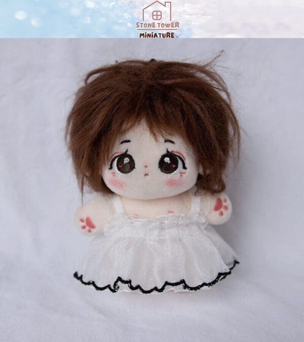 Cute plush doll with brown hair and big eyes, wearing a white dress with black trim, on a white background.