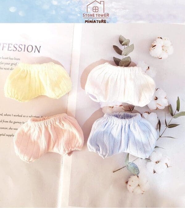 Four colorful miniature bloomers on a book page with cotton flowers and leaves nearby.