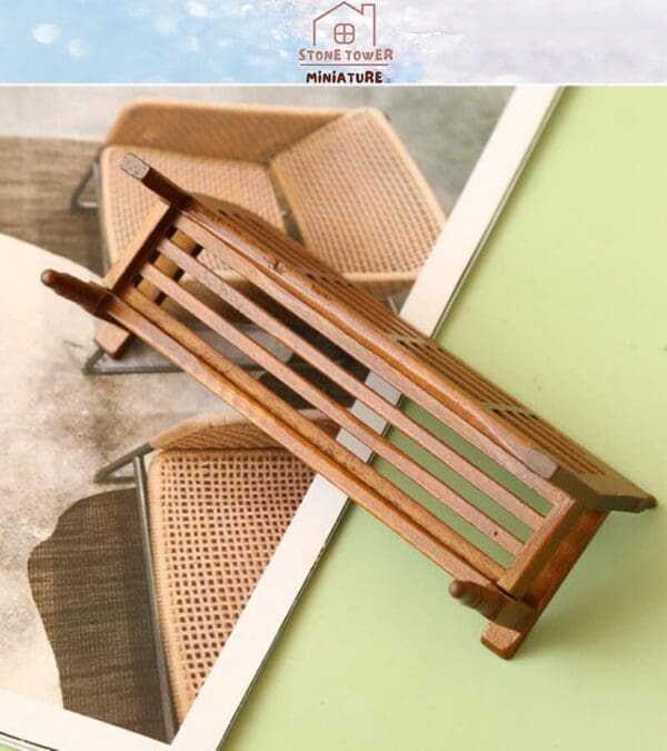 Miniature wooden bench placed on a magazine with wicker chair images, on a green surface.