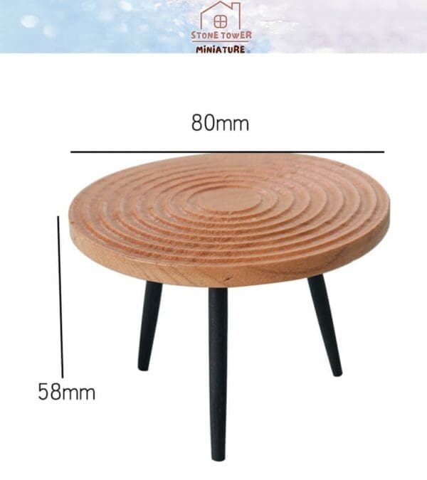 Miniature round wooden table, 80mm wide and 58mm tall, with black legs and concentric design.