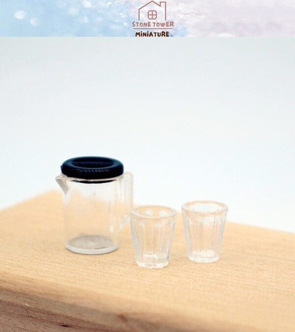 Miniature clear plastic pitcher and two matching glasses on a wooden surface.