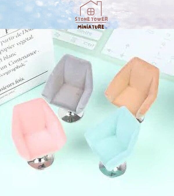 Four miniature chairs in pastel colors: grey, peach, pink, and blue, arranged on a light green surface.