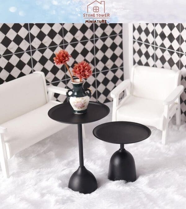 Miniature living room with white chairs, black tables, and a vase with flowers, against a checkerboard-pattern wall.