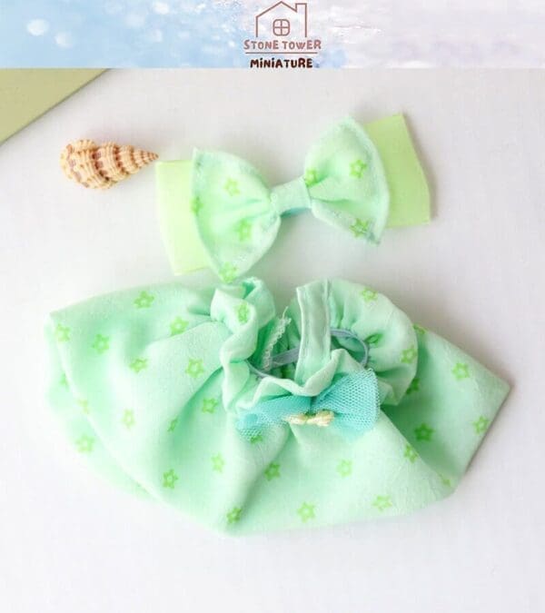 Mint green doll dress and bow set with star patterns and a small seashell accent.