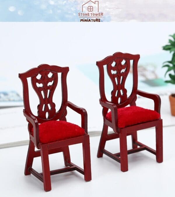 Two ornate miniature red wooden chairs with red velvet seats on a white surface.