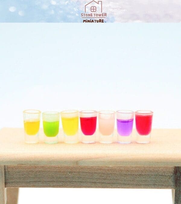 Seven colorful miniature drinks on a wooden table.