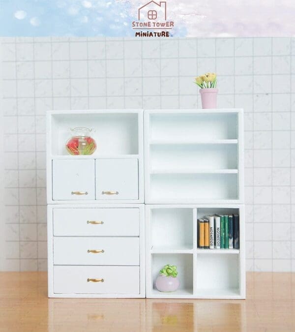 Miniature white cabinet with drawers and shelves, featuring a small plant, books, and a fishbowl on a wooden surface.