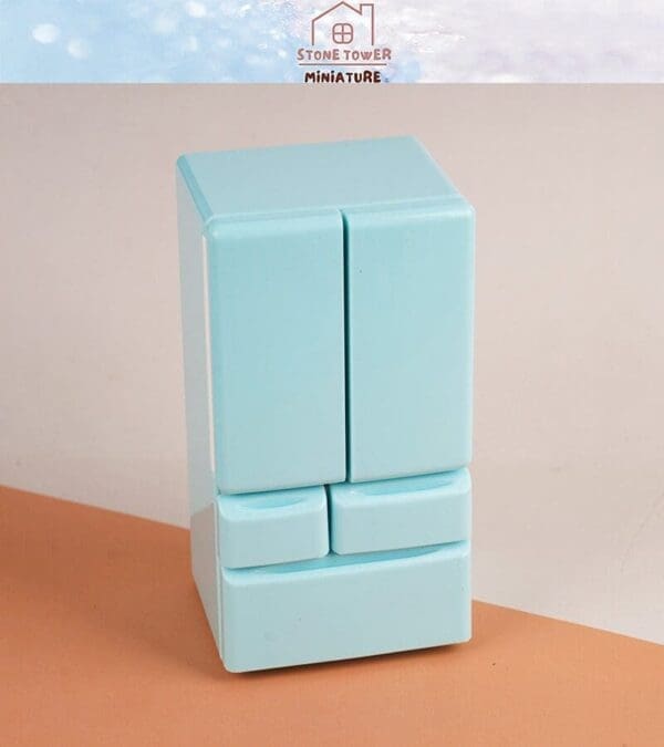 Miniature pastel blue refrigerator with two main doors and two drawers, displayed on a brown surface.