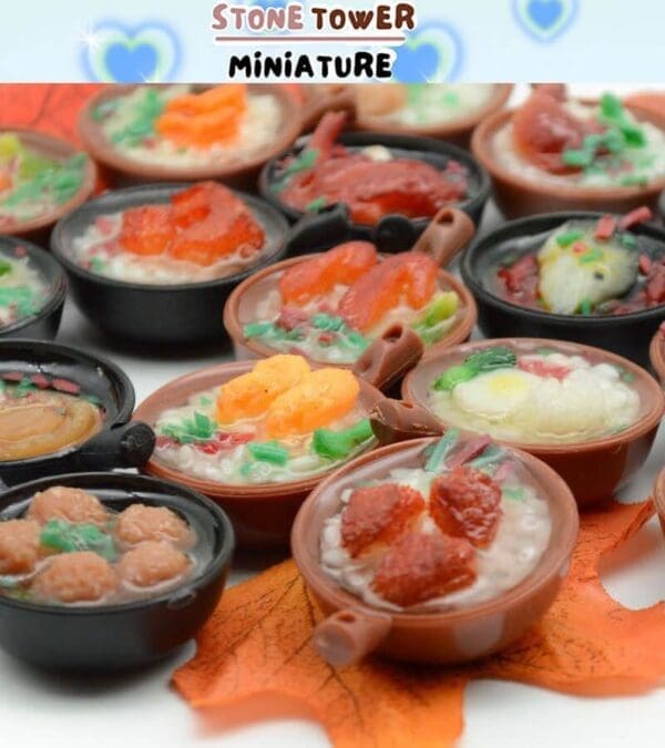 Miniature bowls of vibrant soup replicas displayed on an orange leaf, labeled "Stone Tower Miniature.