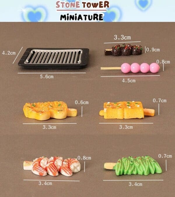 Miniature grill set with food items: chocolate sticks, pink balls, cheese skewers, shrimp skewers, and green noodles.