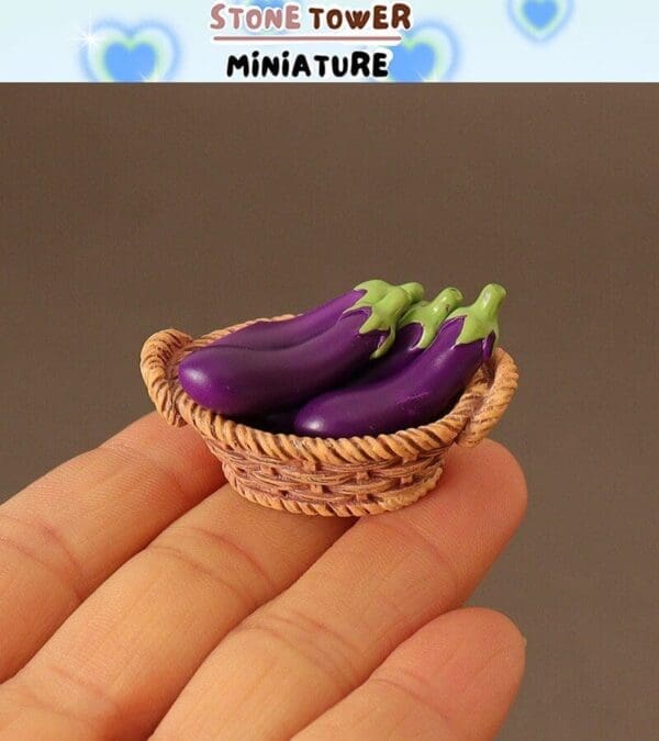 Miniature basket with four tiny eggplants held in a person's hand, showcasing detail and craftsmanship.