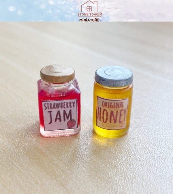 Miniature jars of strawberry jam and original honey on a light surface.