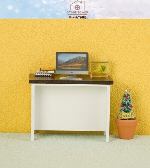 Miniature office setup with a laptop, book, fishbowl, and tiny Christmas tree on a desk against a yellow wall.