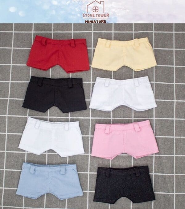 Seven miniature shorts in assorted colors on a grid-patterned fabric.