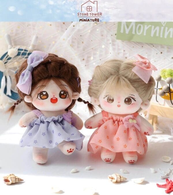 Two cute plush dolls in colorful dresses and matching bows, posed side by side on a bright, decorated surface.