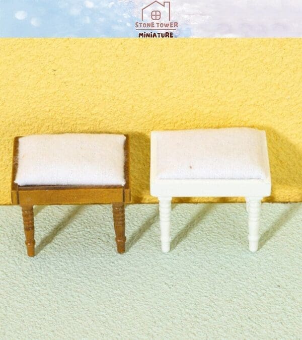 Two miniature cushioned stools, one brown and one white, on a textured surface with a yellow and blue background.