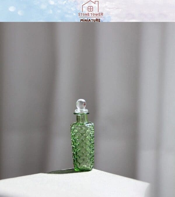 Miniature green glass bottle with a textured surface and clear stopper on a white surface.