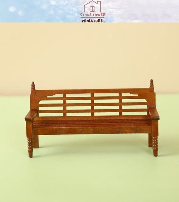 Miniature wooden bench with slatted backrest and armrests on a pastel background.