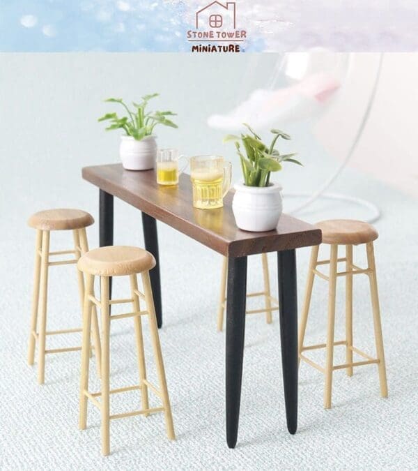 Miniature wooden table with four stools, potted plants, and two glass mugs. Background shows a soft light blue surface.