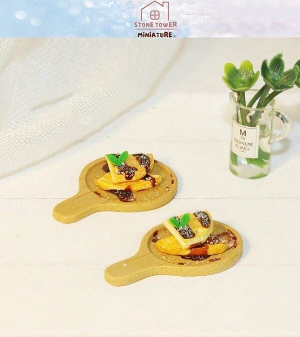 Miniature pancakes with syrup and garnish on wooden trays, next to a small vase with green leaves.