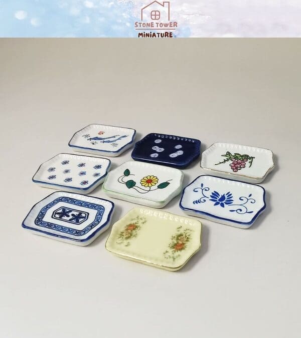 Collection of miniature ceramic plates with various floral and abstract designs, arranged on a light background.